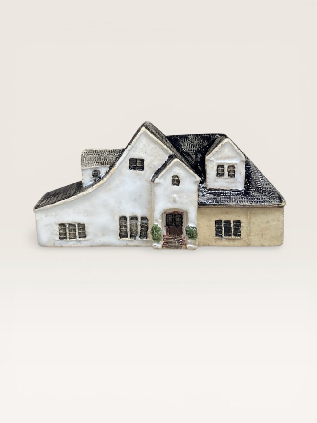 Architectural ceramic replica of a modern suburban house with white walls, black multi-gable roof, and porch details.
