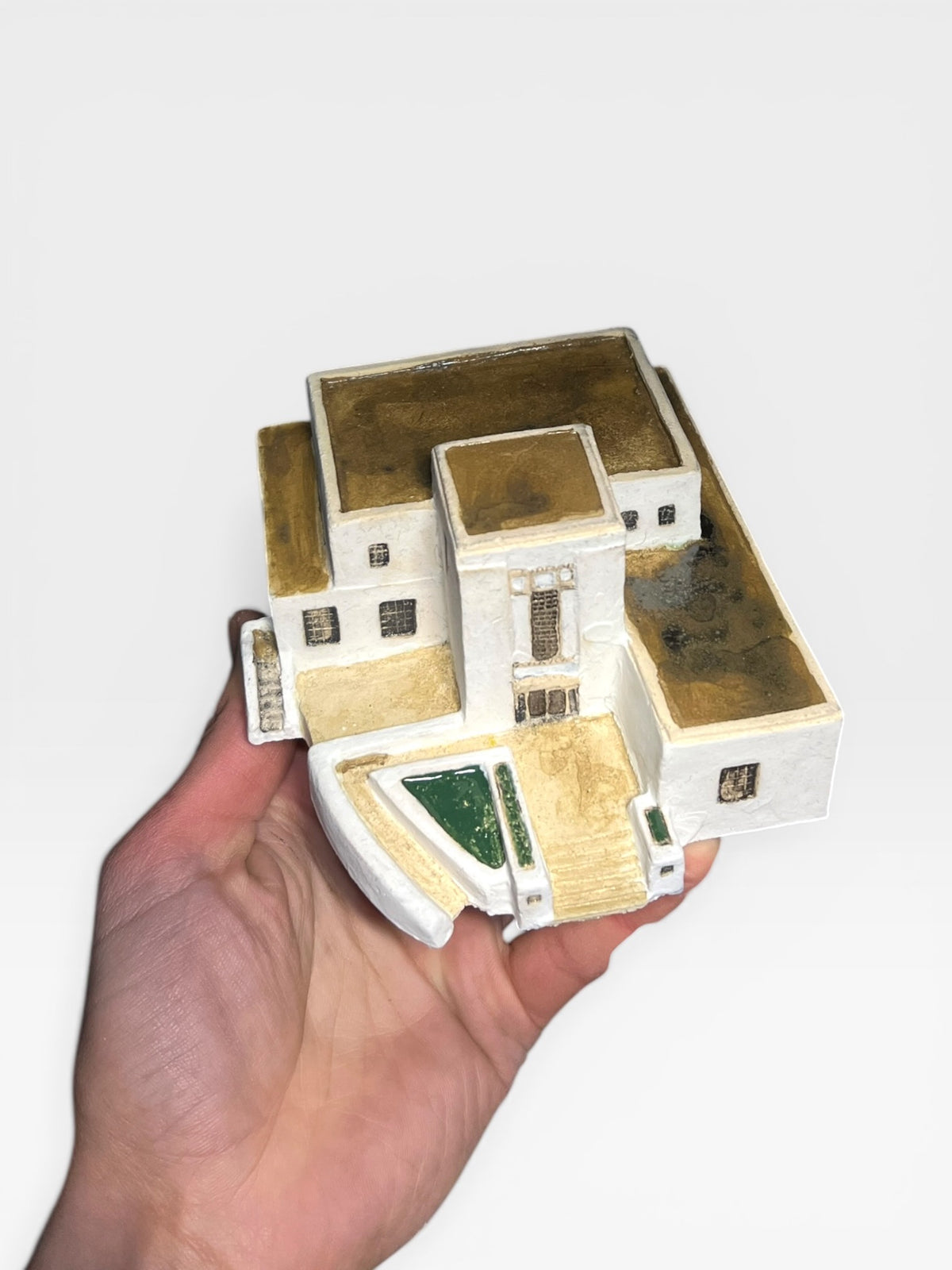 Custom hand-sculpted ceramic model of a modern white Mediterranean villa with terraced levels and steps.