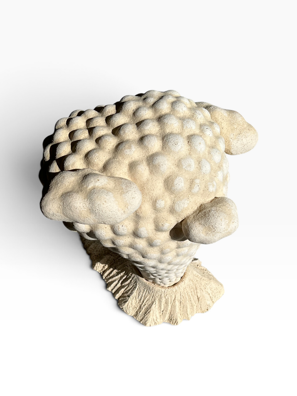 Front view of the "Volcano" ceramic sculpture with textured bubbled body and carved base made of beige stoneware.